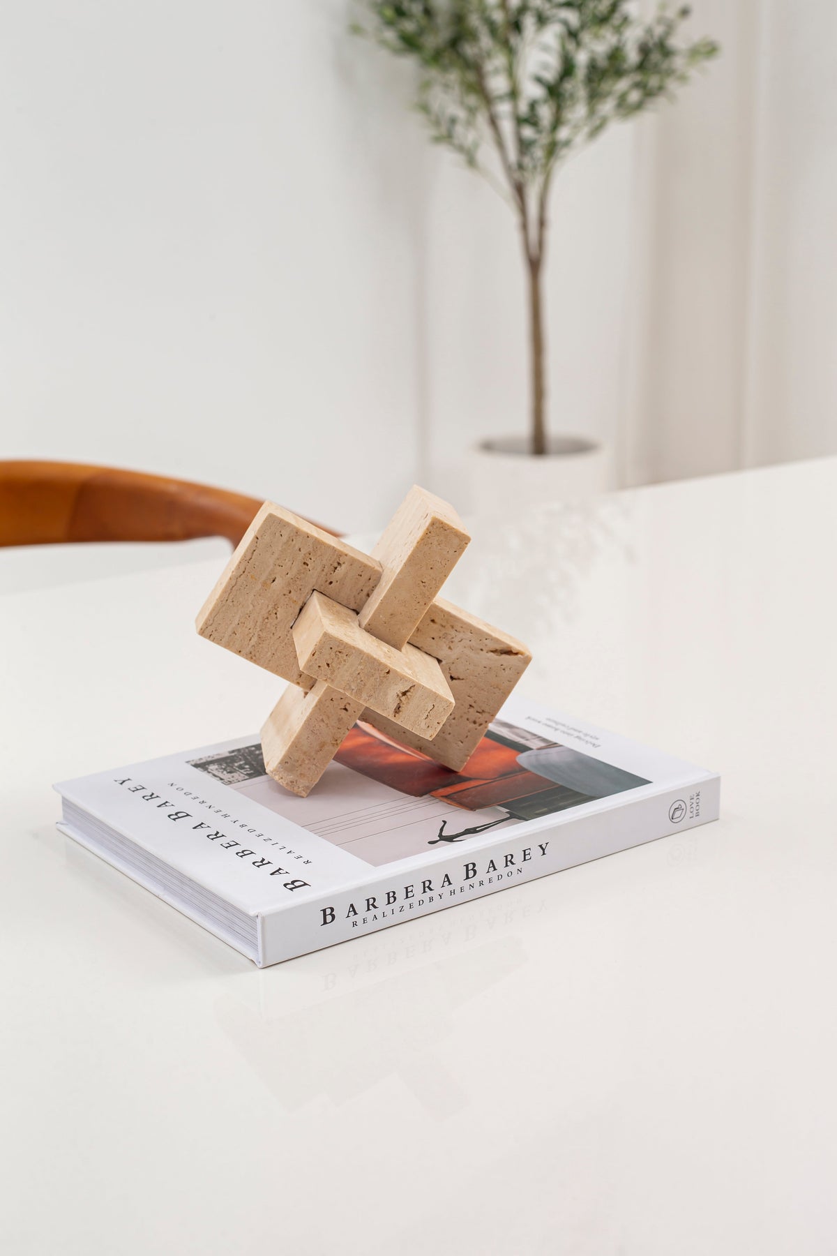 Sculpture nœud en travertin posée sur un livre