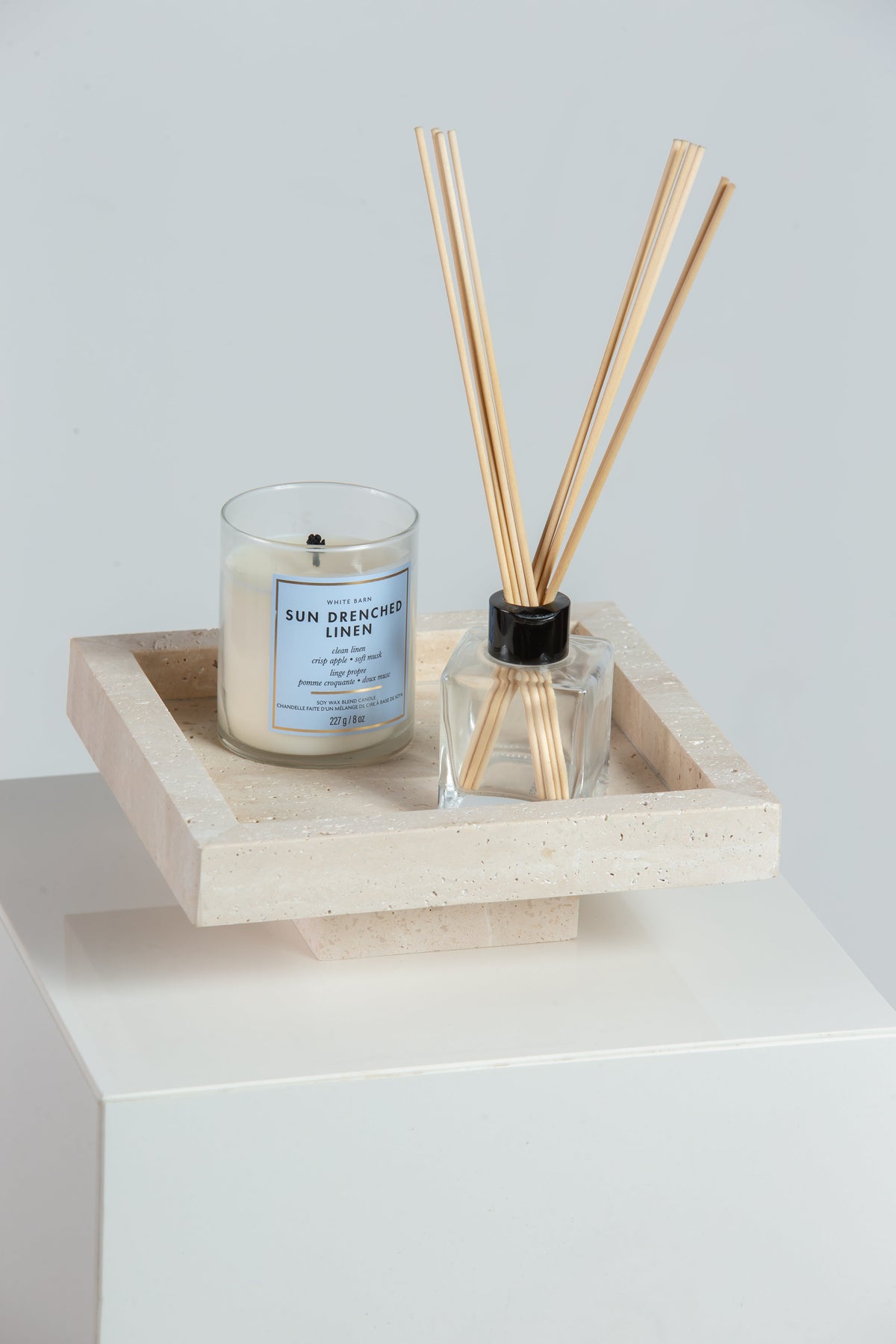 Plateau sur socle en travertin beige avec bougie et diffuseur