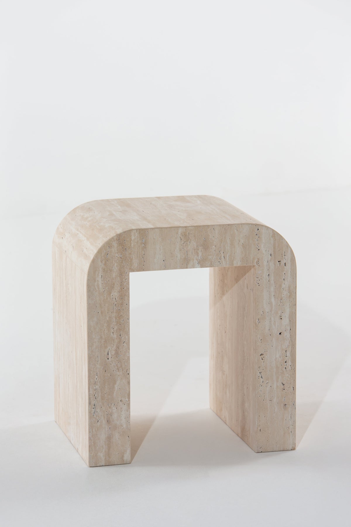 Table d'appoint en arche en travertin vue de trois quarts