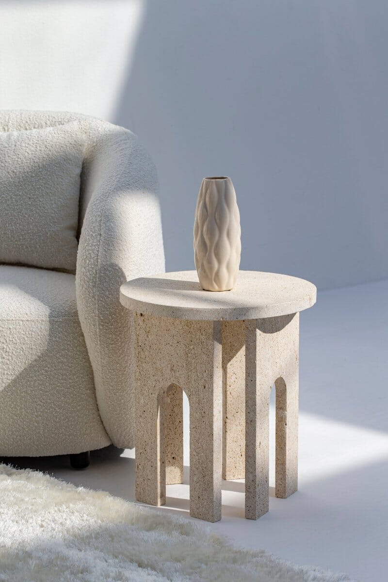 Table d'appoint Romana en travertin à côté d'un fauteuil