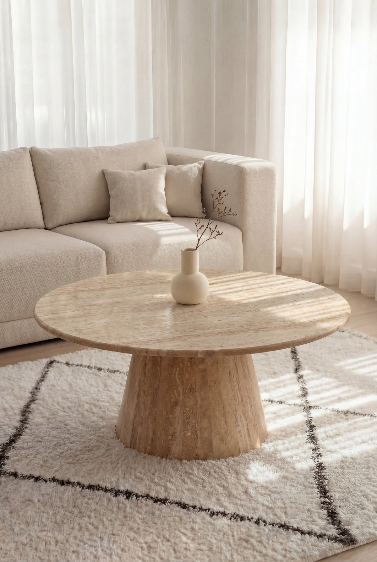 Table basse ronde en travertin Méridia sur pied conique dans un salon