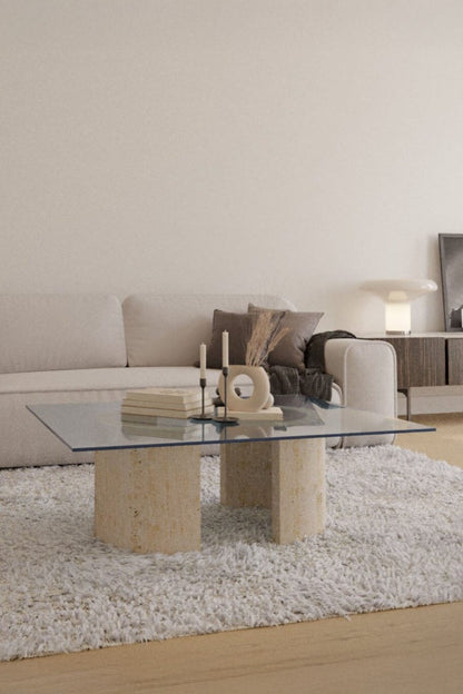 Table basse Nordika en verre sur pieds en U en travertin dans un salon